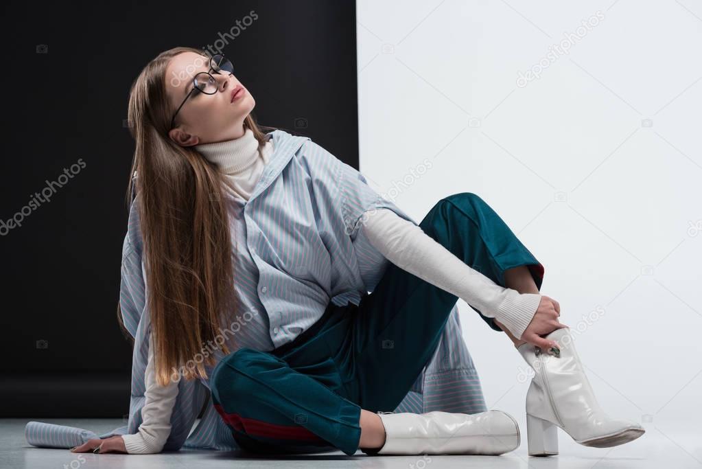 woman in stylish outfit sitting on floor