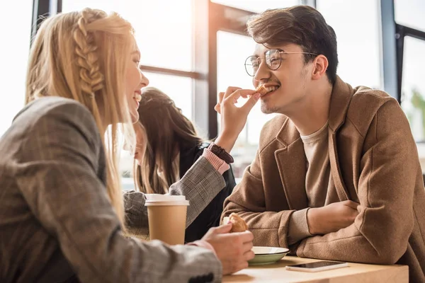 Girlfriend giving piece of croissant to boyfriend — Stock Photo, Image