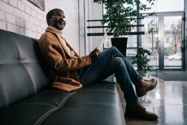 Tablet ile oturan orta yaşlı adam