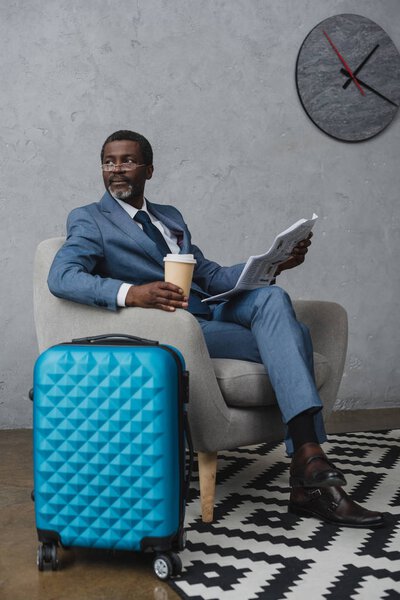 человек читает газету и держит кофе
