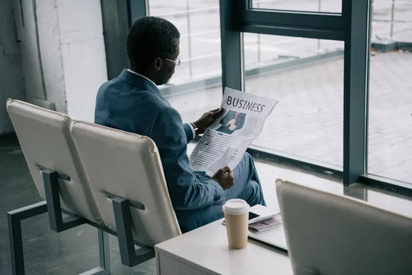 Empresario leyendo periódico en aeropuerto — Foto de Stock