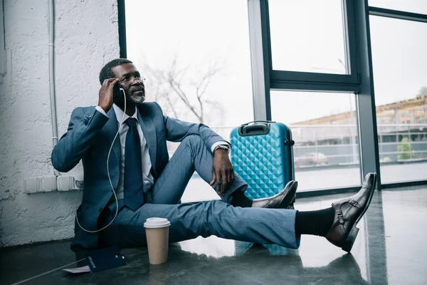 Businessman sitting on floor and talking by smartphone — Stock Photo, Image