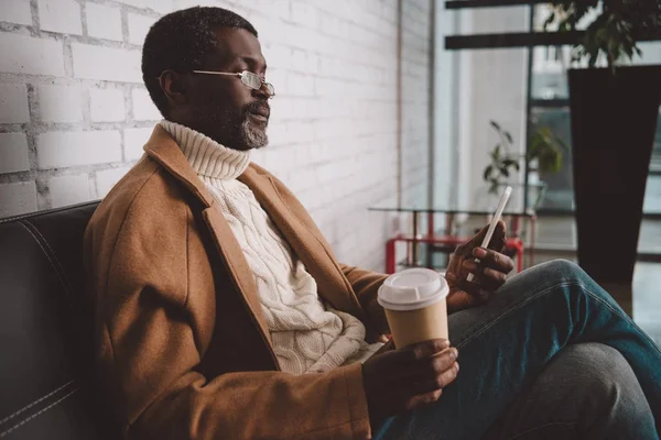 Kahve tutarak ve smartphone vasıl arayan adam — Ücretsiz Stok Fotoğraf