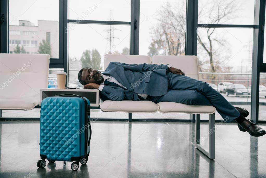 businessman napping on chairs at airport