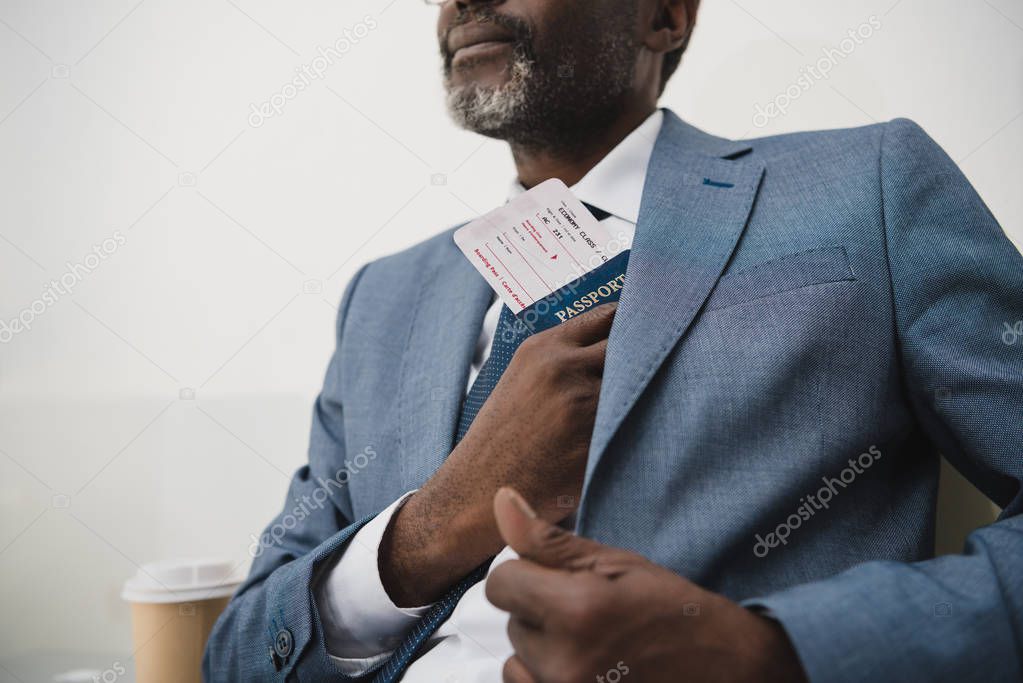 man hiding passport and ticket in suit