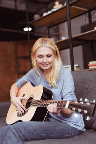 middle aged woman with guitar at home