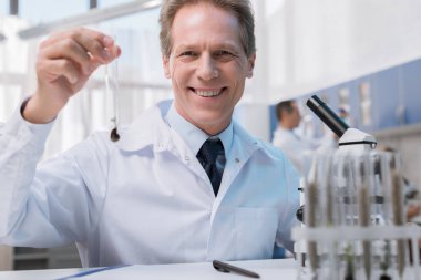 Smiling chemist holding test tube  clipart