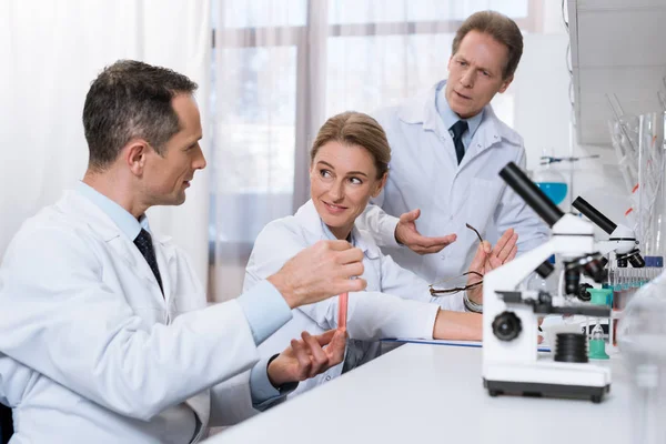 Científicos examinando tubo de ensayo — Foto de Stock