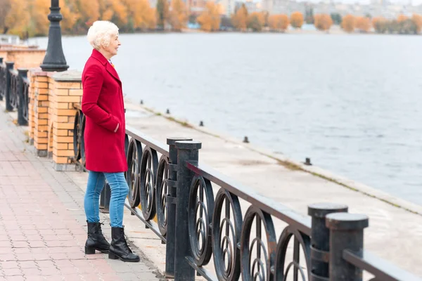 Woman in red coat on quay — Free Stock Photo