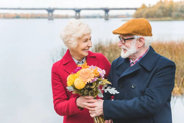 Happy senior couple with bouquet — Stock Photo, Image