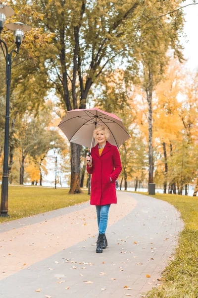 Жінка з парасолькою в осінньому парку — стокове фото