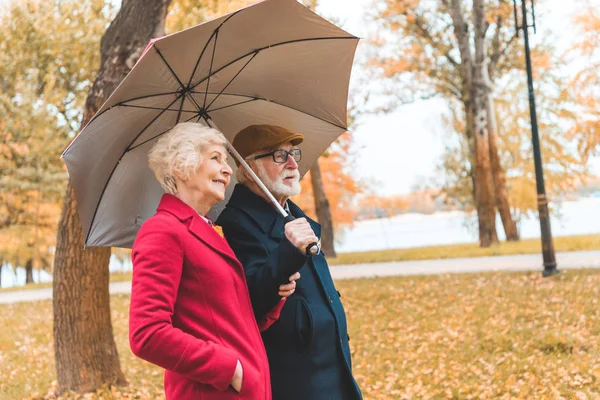 Старша пара з парасолькою в парку — стокове фото