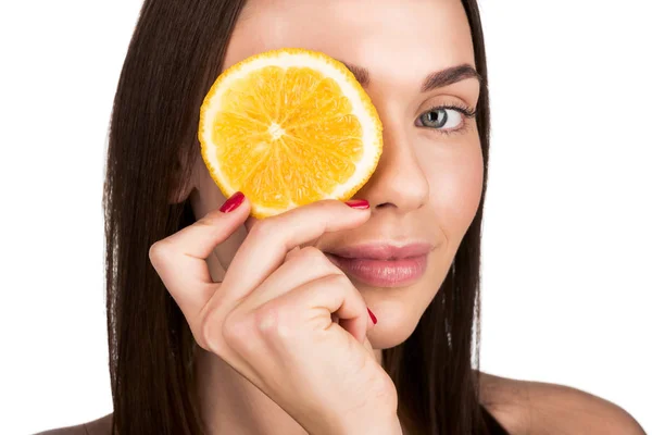 Mulher cobrindo olho com fatia de laranja — Fotografia de Stock