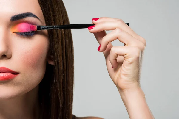 Mulher aplicando sombras coloridas — Fotografia de Stock