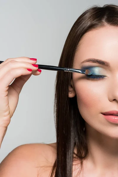 Mujer joven aplicando sombra de ojos — Foto de Stock