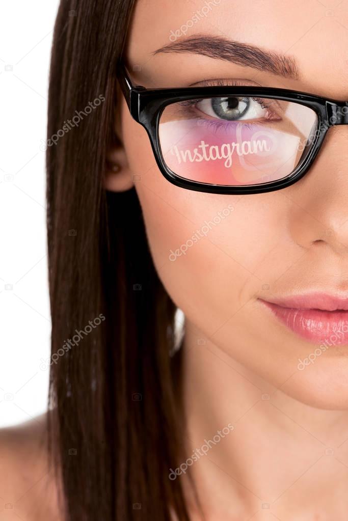 Portrait of young woman with instagram logo reflection in eyeglasses isolated on white