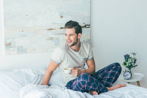 man drinking coffee on bed