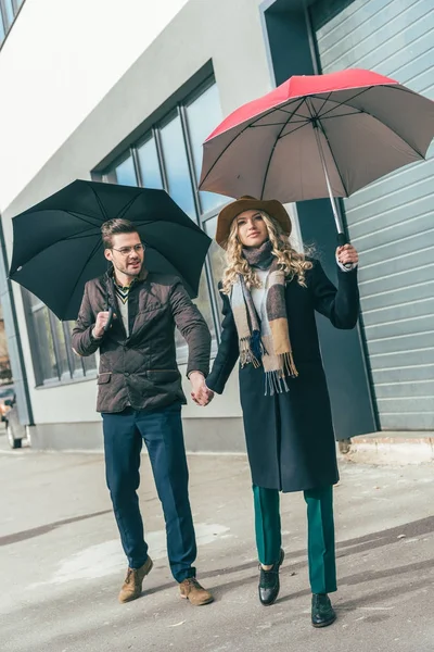 Pareja joven con estilo con sombrillas — Foto de Stock