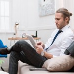 Businessman using digital tablet while sitting on sofa at home