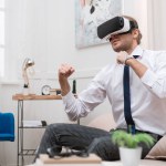 Affärsman kämpar och använder virtuell verklighet headset när du sitter på soffan hemma