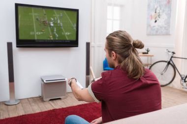 Uzaktan kumanda ile evde maç futbol izlerken arkadan görünüşü adam