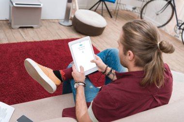 man sitting on sofa while using digital tablet with skype appliance clipart