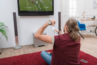 Arkadan görünüş adam futbol maçı izlerken ve evde tezahürat 