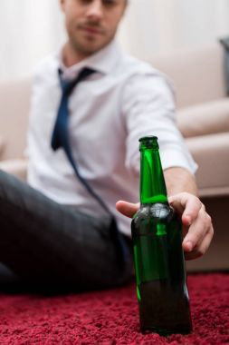 Adam alarak şişe bira oturma odasında bir halı üzerinde otururken