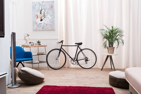 Bicycle standing in a living room near the window