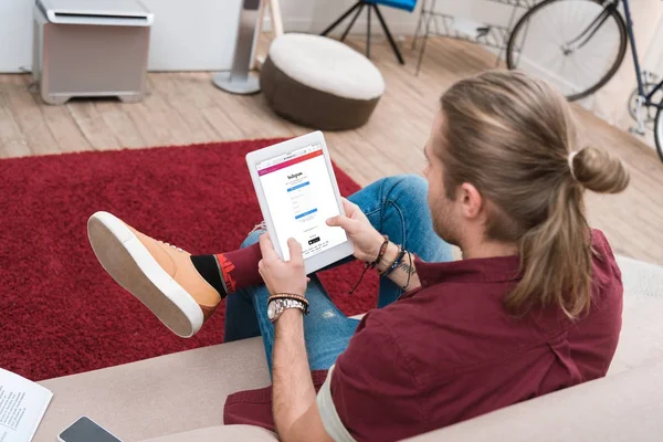 Instagram のアプライアンスでデジタル タブレットを使用している間 ソファーに座っていた男 — ストック写真