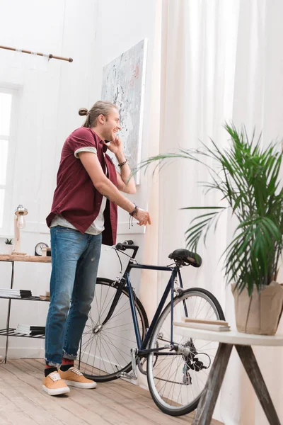 Bonito Alegre Homem Falando Smartphone Com Bicicleta Casa — Fotografia de Stock