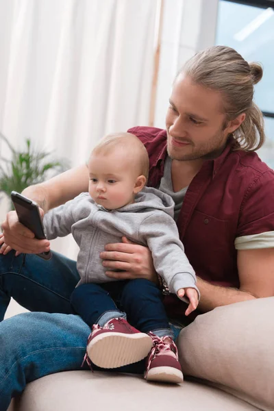 Szczęśliwy Ojciec Siedzi Małego Synka Przy Użyciu Smartfona — Zdjęcie stockowe