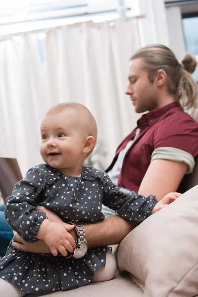 Pequeña Hija Sonriente Sentada Sofá Mientras Padre Usa Computadora Portátil — Foto de Stock