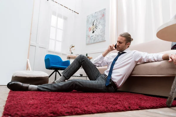 Geschäftsmann Sitzt Hause Auf Rotem Teppich Und Spricht Smartphone — kostenloses Stockfoto