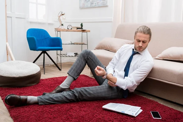 リビング ルームのカーペットの上に座って 新聞を読むビジネスマン — ストック写真