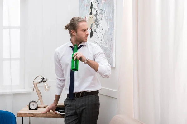 Schöner Mann Steht Wohnzimmer Und Hält Eine Flasche Bier Der — kostenloses Stockfoto