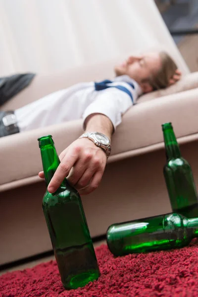 Pijany Mężczyzna Śpi Kanapie Trzymając Butelkę Piwa — Zdjęcie stockowe