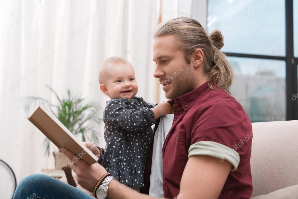 father reading book to little baby girl at home