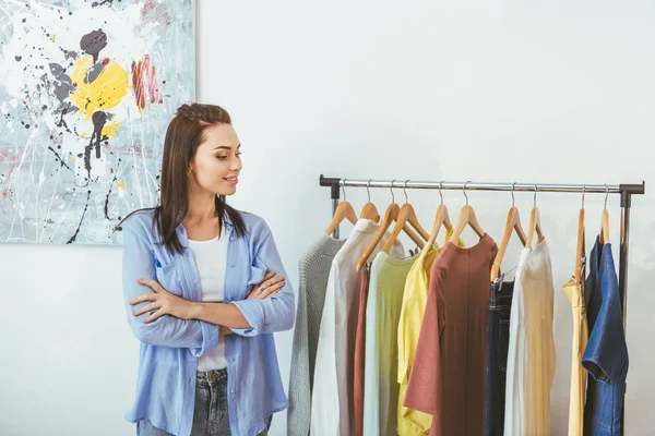 Designer Sorridente Com Mãos Cruzadas Olhando Para Roupas — Fotografia de Stock