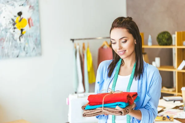 Smiling Seamstress Holding Stack Colored Fabric — Stock Photo, Image