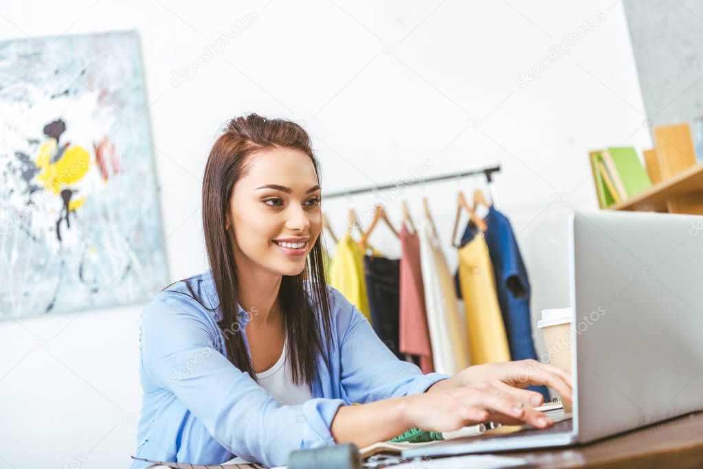 smiling dressmaker using laptop at work 
