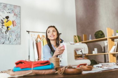 dikiş makinesi oturma ve ararken gülümseyerek terzi