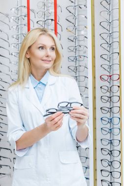 Optik Gözlük raflarda duran profesyonel kadın göz doktoru