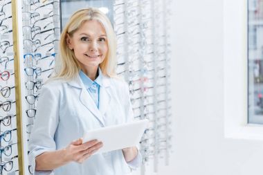 optik gözlük ile tablet ile raflarda çalışan profesyonel kadın göz doktoru