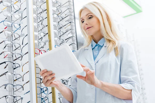Optik Gözlük Raf Ile Tablet Kullanarak Profesyonel Kadın Göz Doktoru — Ücretsiz Stok Fotoğraf