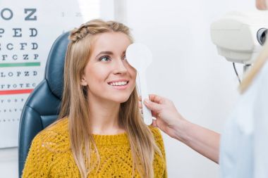 oculist examining beautiful young patient in clinic clipart