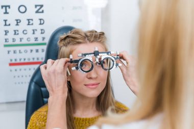 cropped view of oculist and young patient with trial frame in clinic clipart