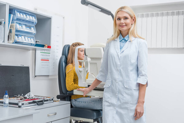 female optometrist examining patient through slit lamp in clinic