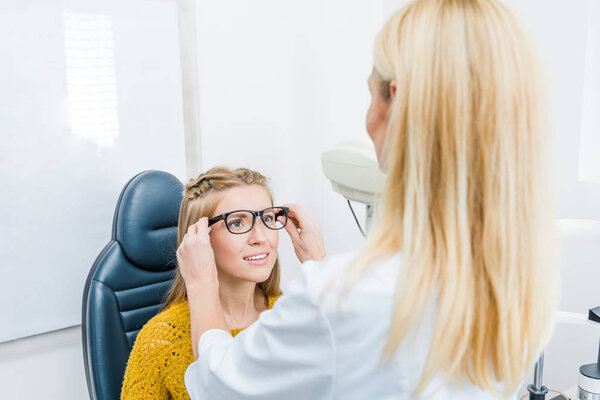 oculist and patient trying new glasses in clinic