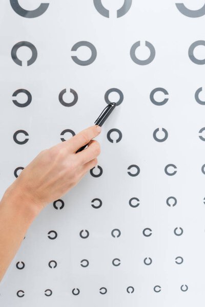 cropped view of optometrist pointing at eye chart 